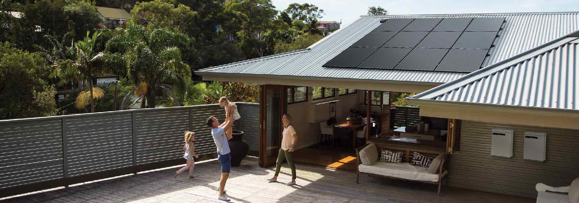 Family playing in backyard of house with Solahart Silhouette solar panels on the roof